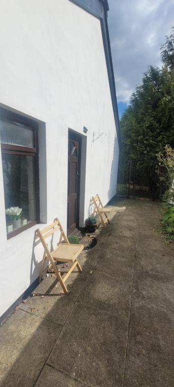 two wooden chairs sitting outside of a white building at Eskdale in Woolton