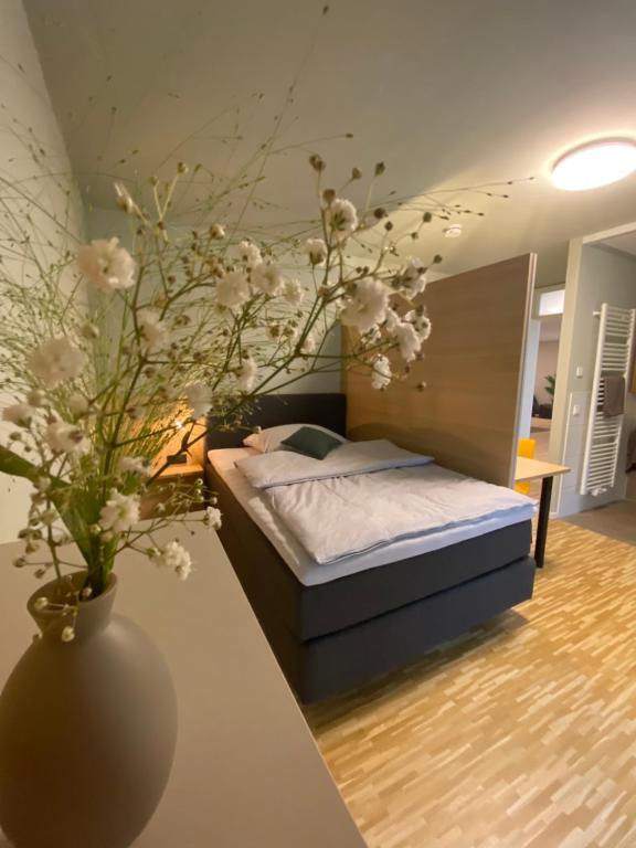 a bedroom with a bed and a vase with flowers at Con4rent Business Hotel plus in Kirchheim unter Teck