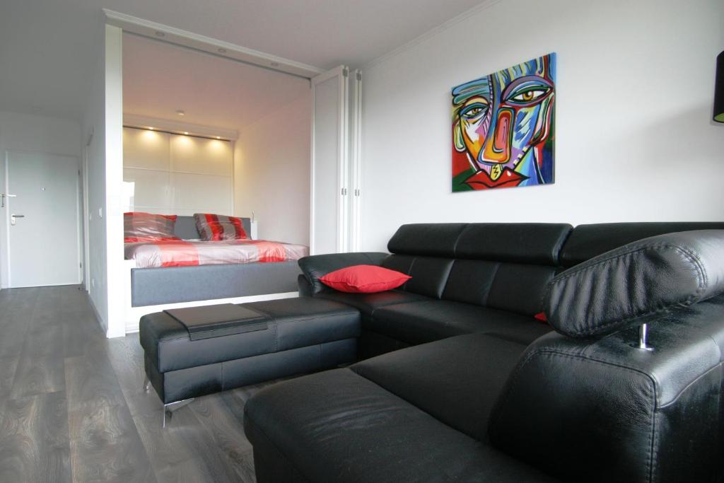 ein Wohnzimmer mit einem schwarzen Sofa und einem Gemälde in der Unterkunft Ferienpark Sierksdorf App 483 - Strandlage in Sierksdorf