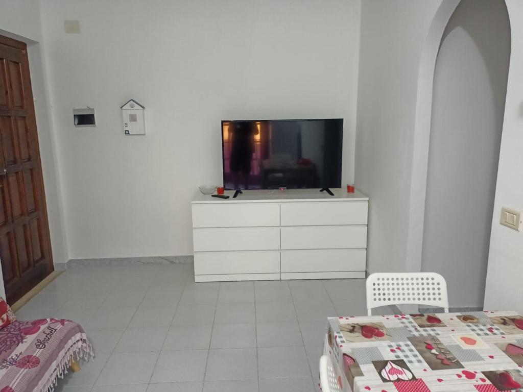 Camera bianca con TV su un comò di Appartamento di 70mq arredato a 600m dal Mare a Scalea