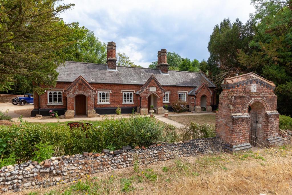 ein altes Backsteinhaus mit einer Steinmauer in der Unterkunft The Georgian - Norfolk Cottage Agency in East Dereham