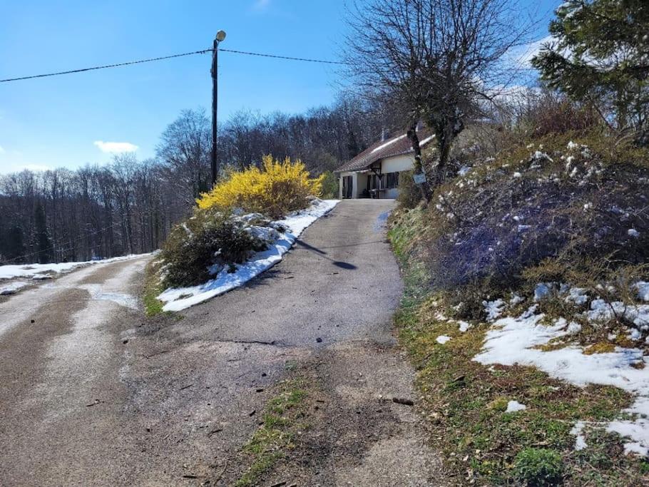 an empty road with snow on the side of a house at Gîte à la ferme du Lomont 