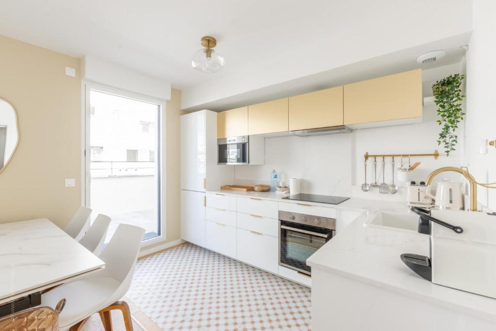 - une cuisine avec des placards blancs, un évier et une table dans l'établissement La Bella Vita By Plaza, à Chessy