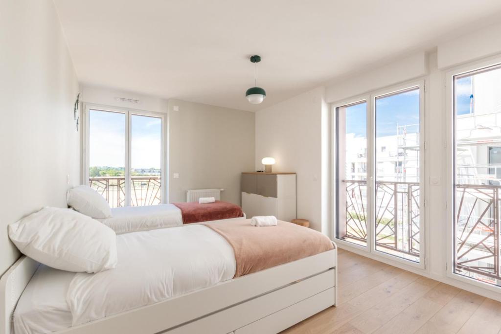 a white bedroom with two beds and a balcony at La Bella Vita By Plaza in Chessy