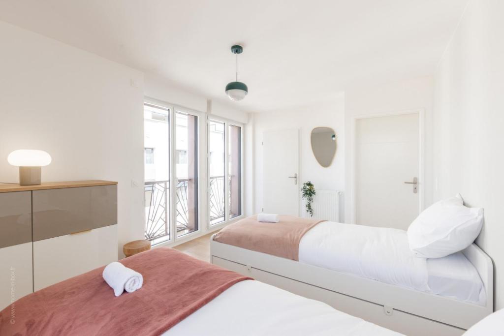 two beds in a bedroom with white walls and windows at La Bella Vita By Plaza in Chessy
