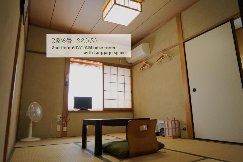 um quarto com uma mesa, uma janela e uma placa em Guest House Atagoya em Quioto