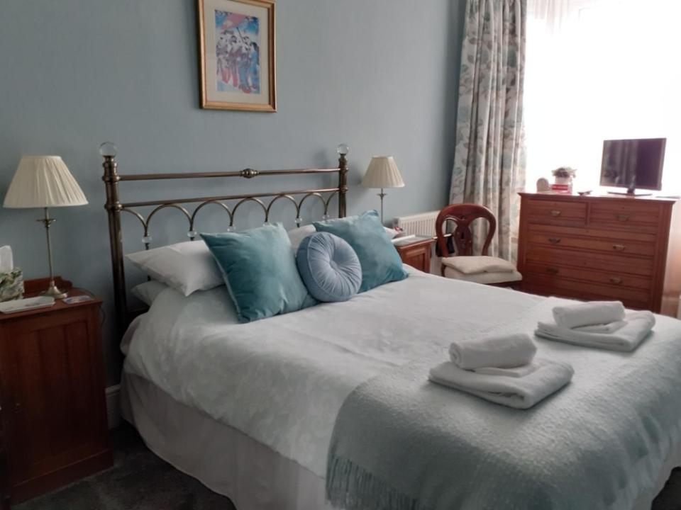 um quarto com uma cama grande e toalhas em Wyburn House em Great Torrington