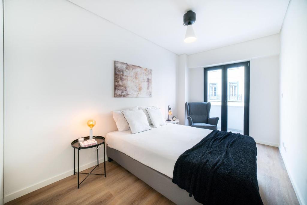 Lusíadas 53 2ºD - Beautiful two-bedroom apartment في لشبونة: غرفة نوم بيضاء بسرير وكرسي