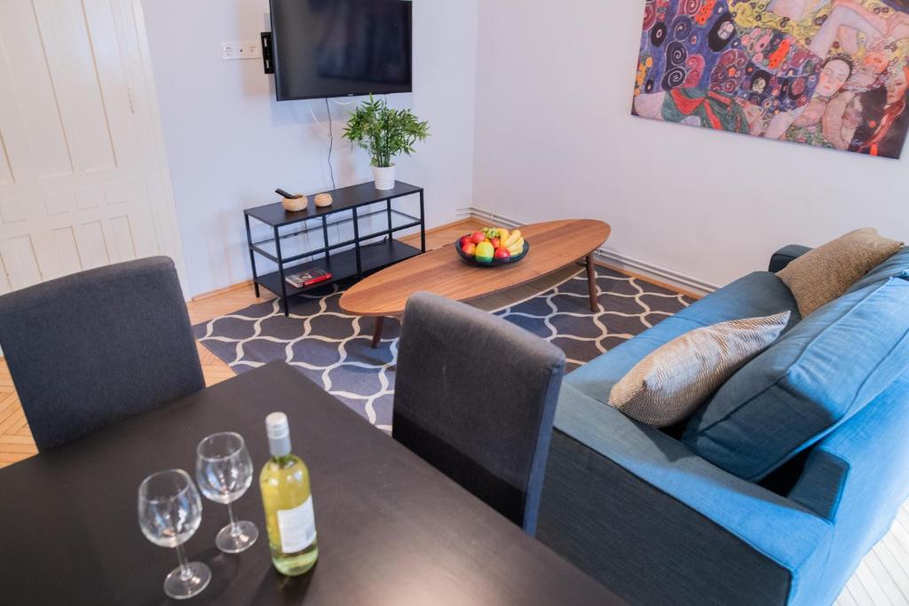 uma sala de estar com um sofá e uma mesa com copos de vinho em Super Comfort Apartment With 3 Rooms Next To Opera em Budapeste