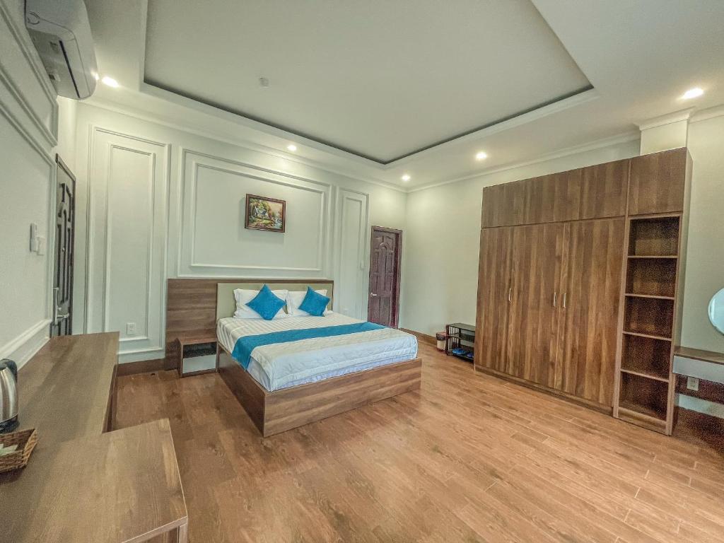 a bedroom with a bed with blue pillows on it at Khách sạn Hoàng Minh Châu Mỹ Phước in Bến Cát