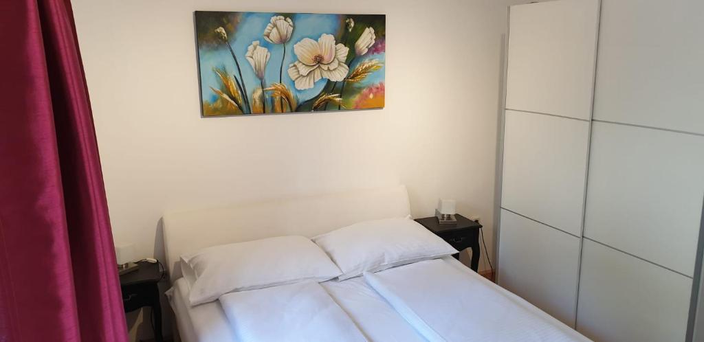 een slaapkamer met een wit bed en een schilderij erboven bij Apartments ONE PALM in Podstrana