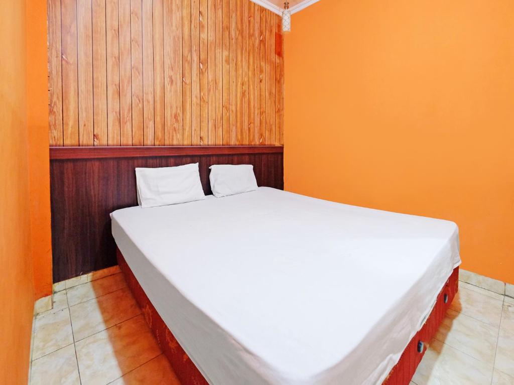 a large white bed in a room with orange walls at Wisma Seruni Palopo in Palopo