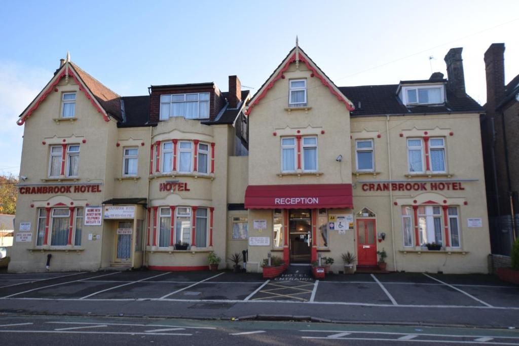 ein Gebäude mit einer roten Tür auf einem Parkplatz in der Unterkunft Cranbrook Hotel in Ilford