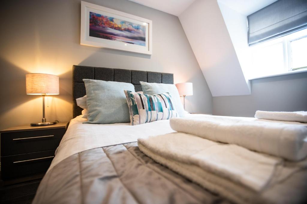 a bedroom with a bed with white sheets and a window at Urban Living's The Hopkins, Beautiful City Apartment with Private Parking in Oxford