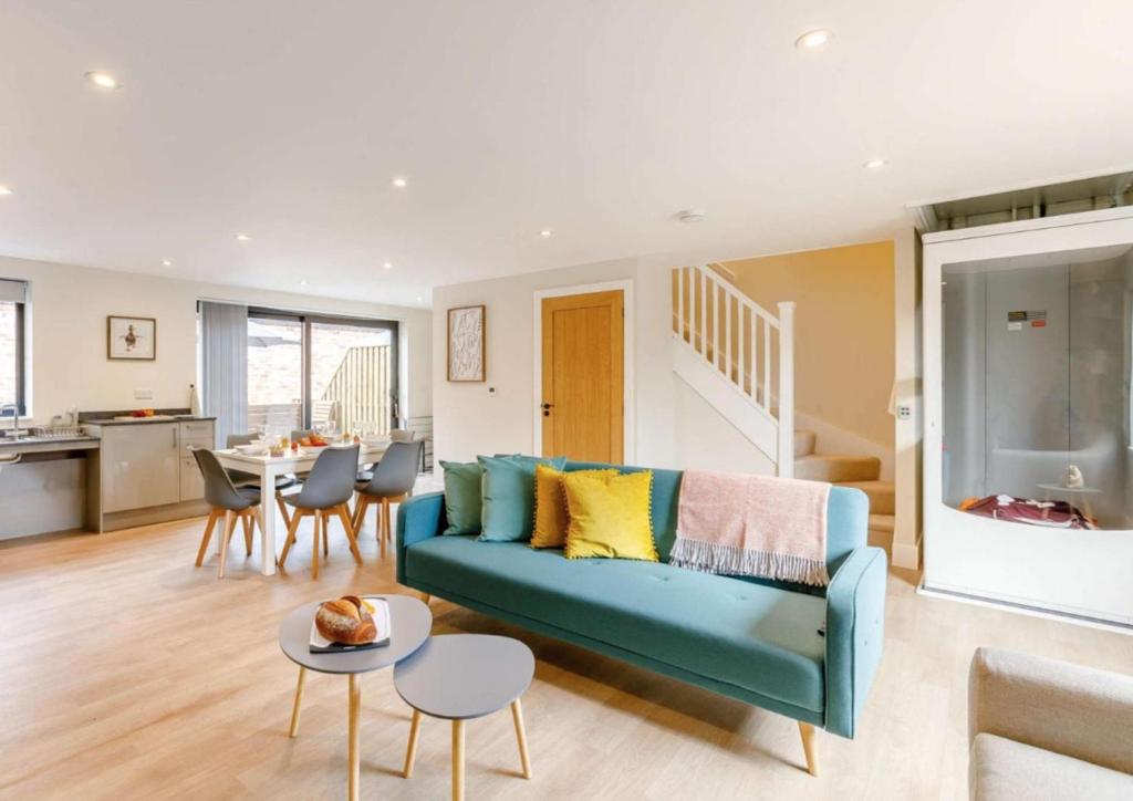 ein Wohnzimmer mit einer blauen Couch und einer Küche in der Unterkunft Fully Accessible-Disabled Adapted-Hot Tub-Pets in Alcester