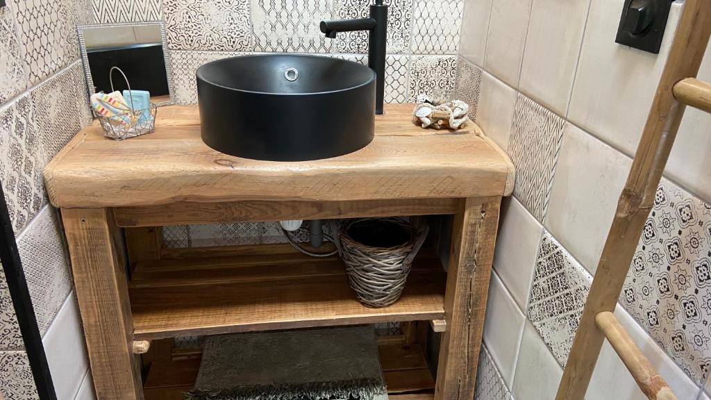 um lavatório preto numa mesa de madeira na casa de banho em La cabane de marie em Arès