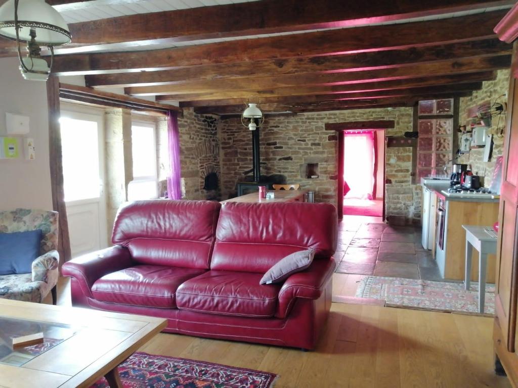 a red couch in a living room with a brick wall at Spacieuse ferme rénovée fin 18ième s. classée 3* in Arpenans