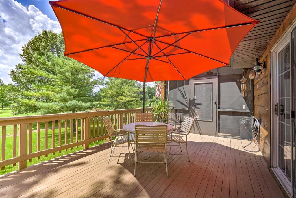 einen Tisch und Stühle auf einer Terrasse mit einem roten Regenschirm in der Unterkunft Updated Buckeye Lake Retreat with Game Room! in Thornville