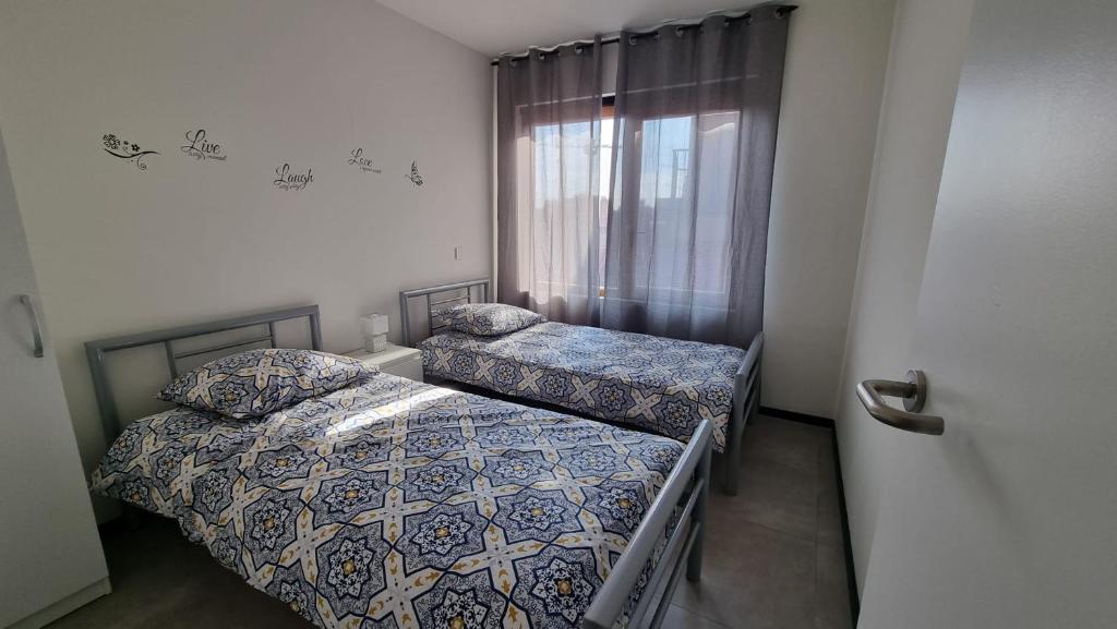 2 camas en una habitación pequeña con ventana en Rossella B&B App 4, en Roeselare