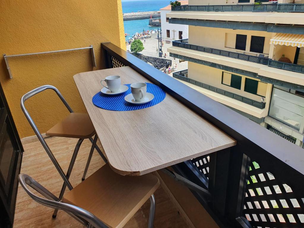 a table on a balcony with two cups on it at Marina Beach in Puerto de la Cruz