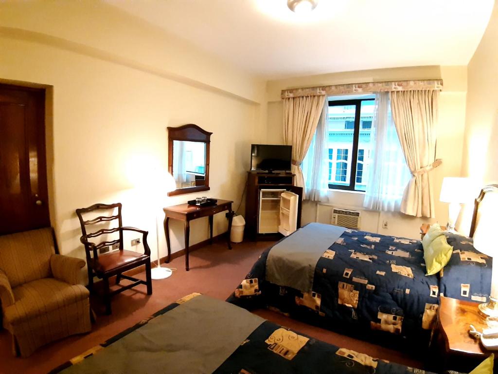 Habitación de hotel con cama y silla en Hotel MAURY en Lima