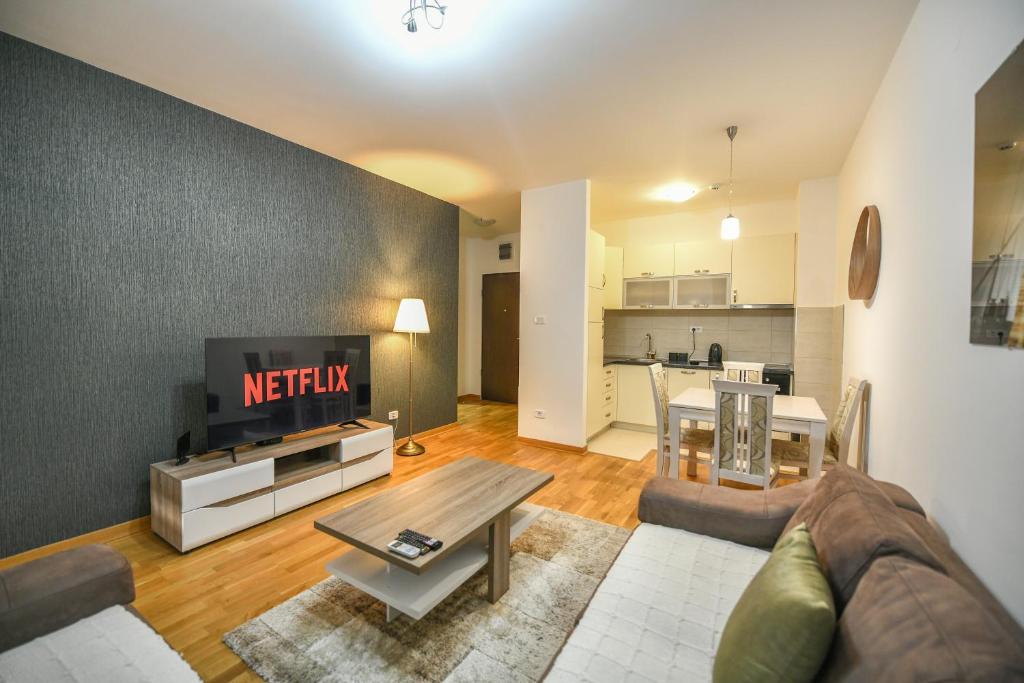 ein Wohnzimmer mit einem Sofa, einem TV und einem Tisch in der Unterkunft Apartment Bono Lux City Kvart in Podgorica