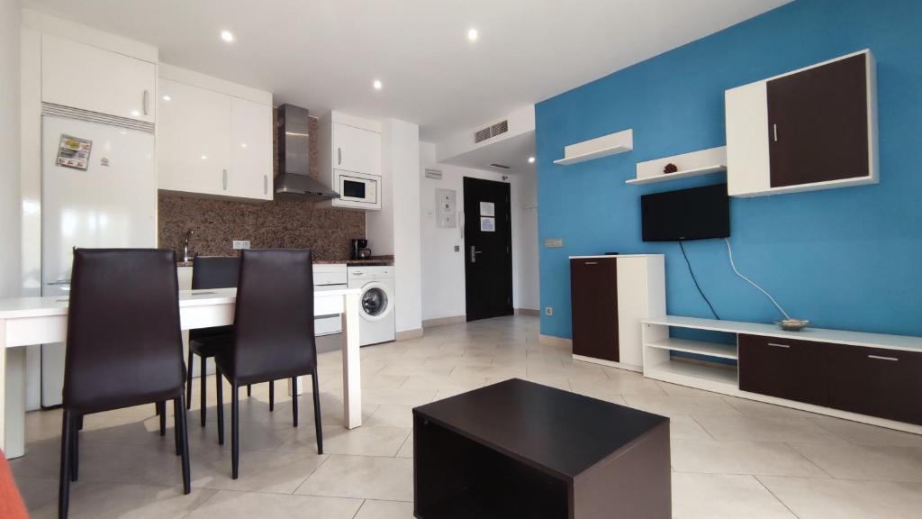 a kitchen with a table and chairs and a blue wall at Apartamentos Cala Azul La Móra in Tarragona