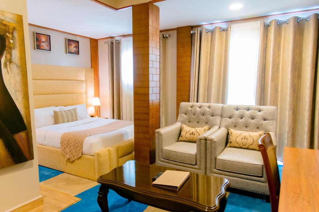 Legend Boutique Hotel في كيغالي: غرفة نوم بسرير وكرسي وطاولة