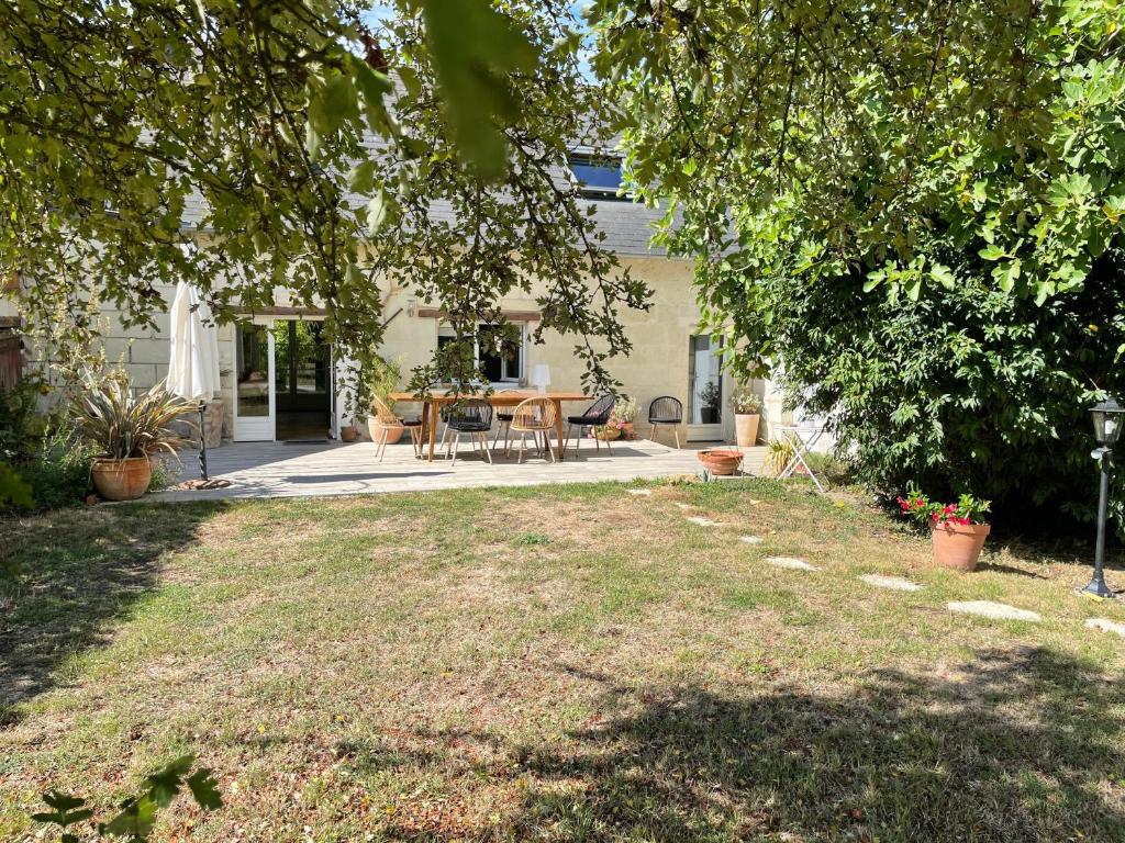 een tuin met een tafel en stoelen voor een huis bij Chambres d hôtes avec Piscine et Spa La Folière Saumur in Villebernier