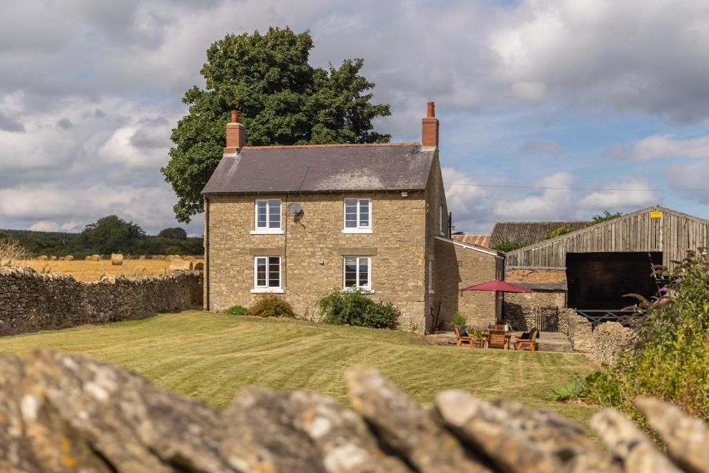 an old stone house with a fence in front of it at Luxury Farmhouse with Stunning Views and Hot Tub in Ebberston