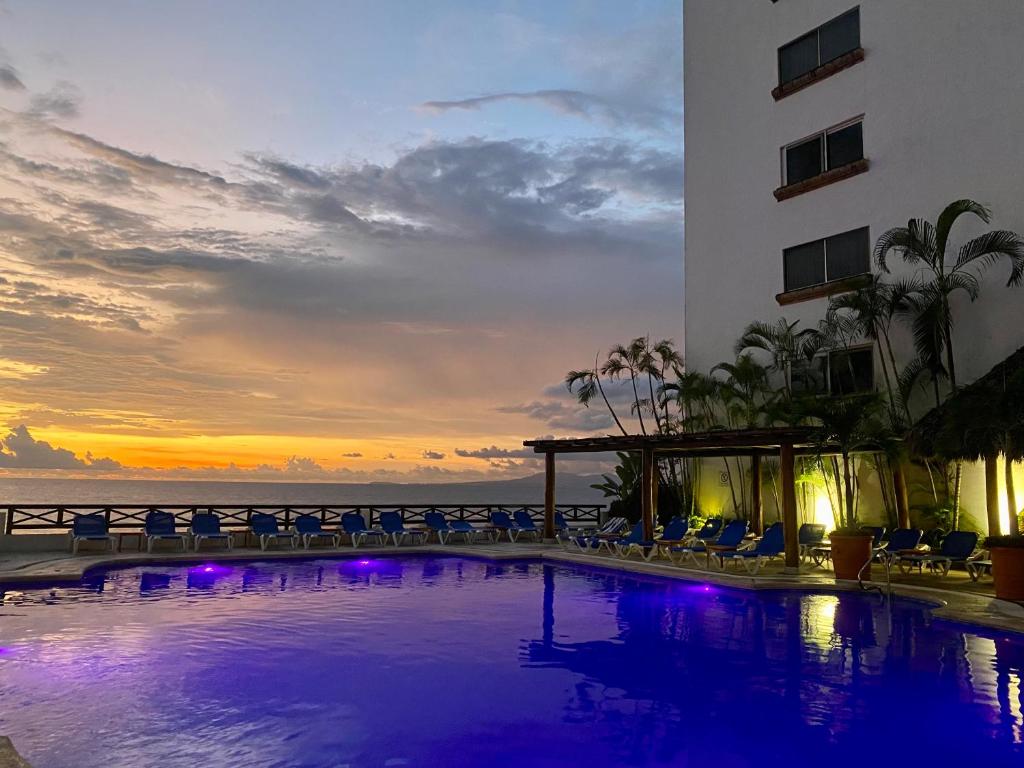 a hotel swimming pool with a sunset in the background at Costa Sur Resort & Spa in Puerto Vallarta