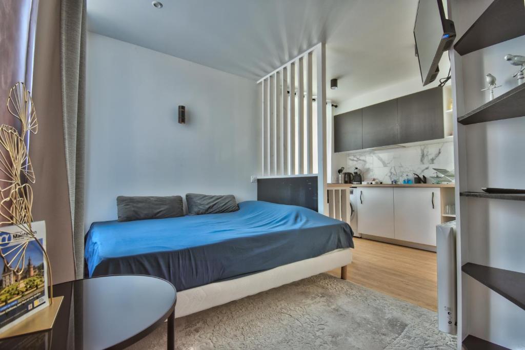 um pequeno quarto com uma cama azul e uma cozinha em Le CoCoN de MaiNteNon em Maintenon