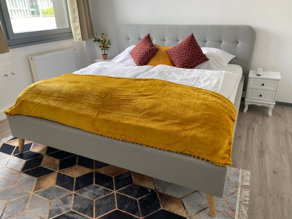 a bedroom with a large bed with a yellow blanket at UrbanSuites - Modern & Zentral in der City - Dein Zuhause in Stuttgart in Stuttgart
