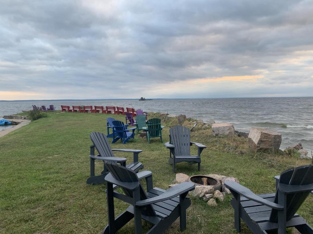 un grupo de sillas sentadas en la hierba cerca del océano en Glen Garry motel and cottages, en North Bay