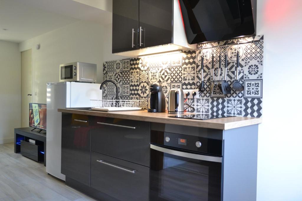 a kitchen with a black and white tiled wall at L&#39;essentiel de Chartres in Chartres