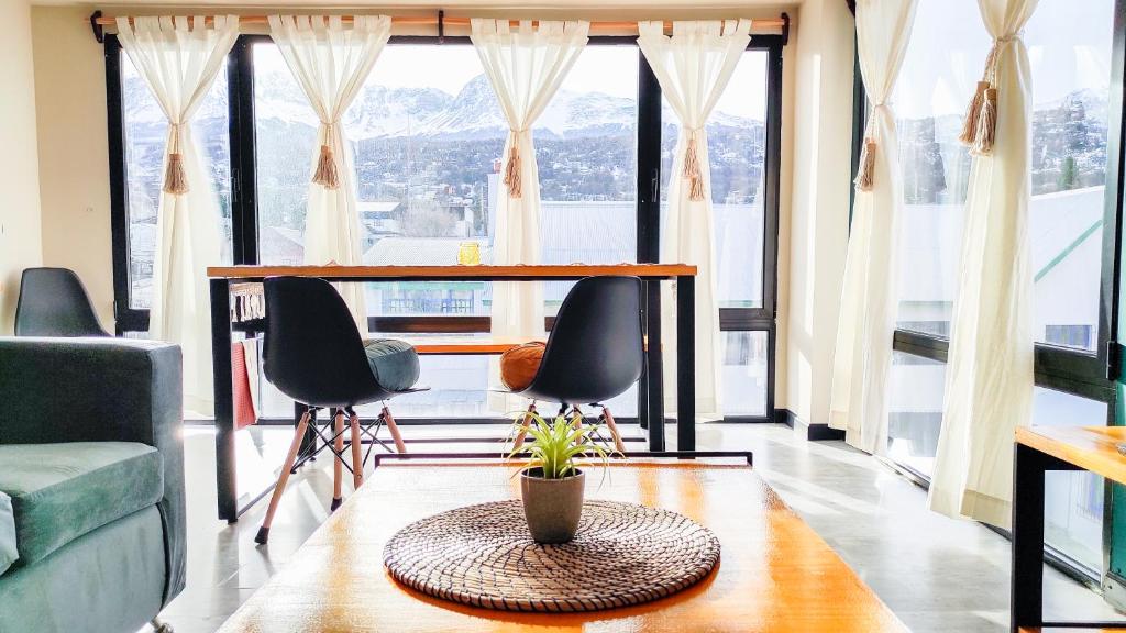 a living room with a table and chairs and large windows at Amanecer del Fuego II in Ushuaia