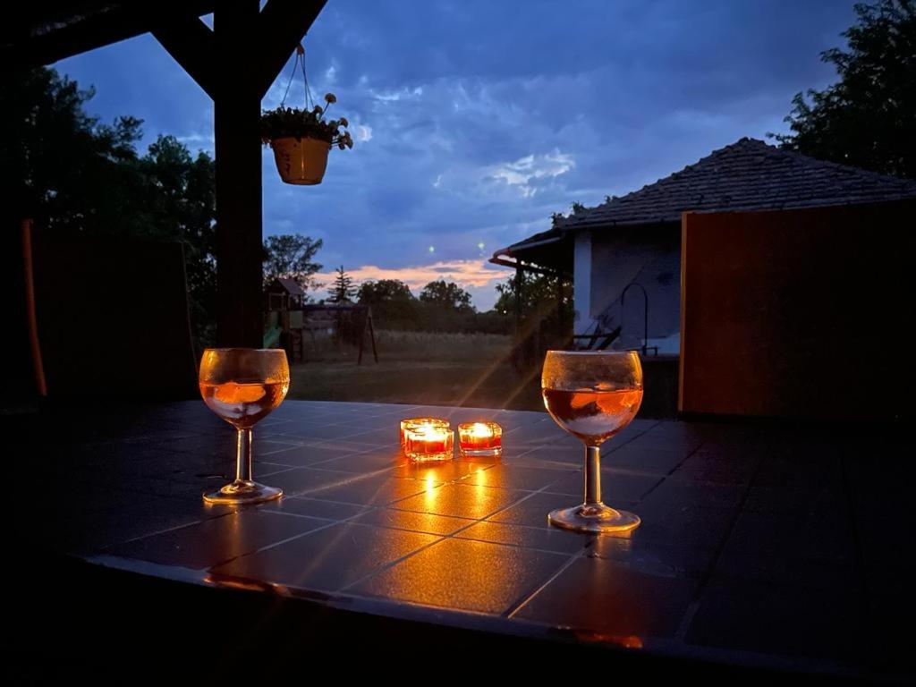 ポロスローにあるFavorite Vendégházのワイングラス2杯(キャンドル付きテーブルに座る)