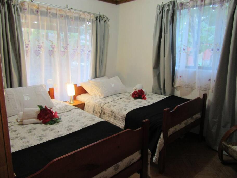 Dos camas en un dormitorio con flores. en Cabañas Hua'ai Village, en Hanga Roa