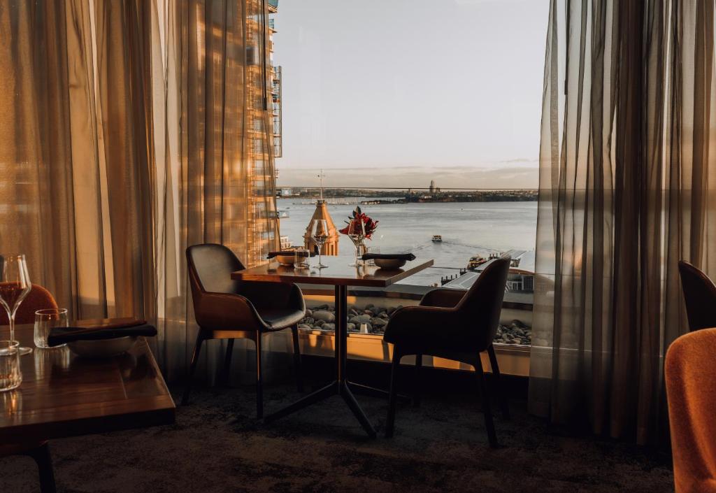 a room with a table and chairs and a large window at Mövenpick Hotel Auckland in Auckland