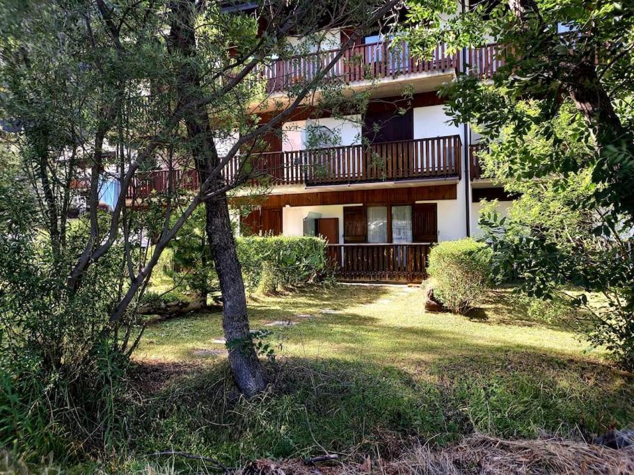 a building with a balcony and a yard with trees at Cesana Pearl in Cesana Torinese