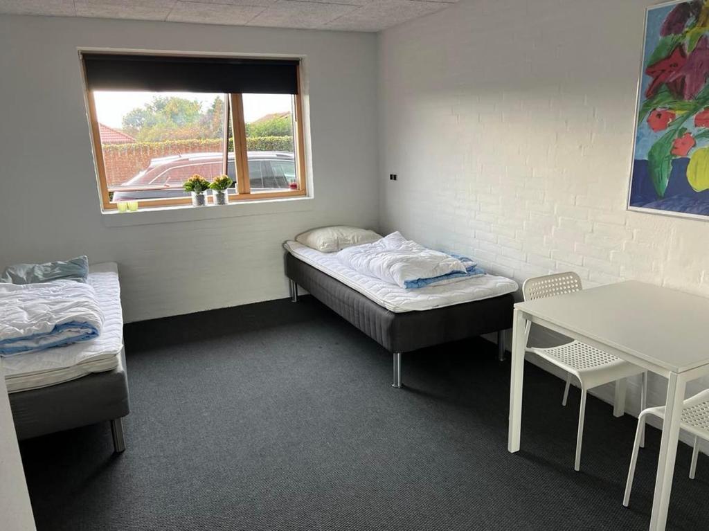 Cette chambre comprend un lit, une table et une fenêtre. dans l'établissement Ebbesens Bed and Bath - two double rooms, à Herning