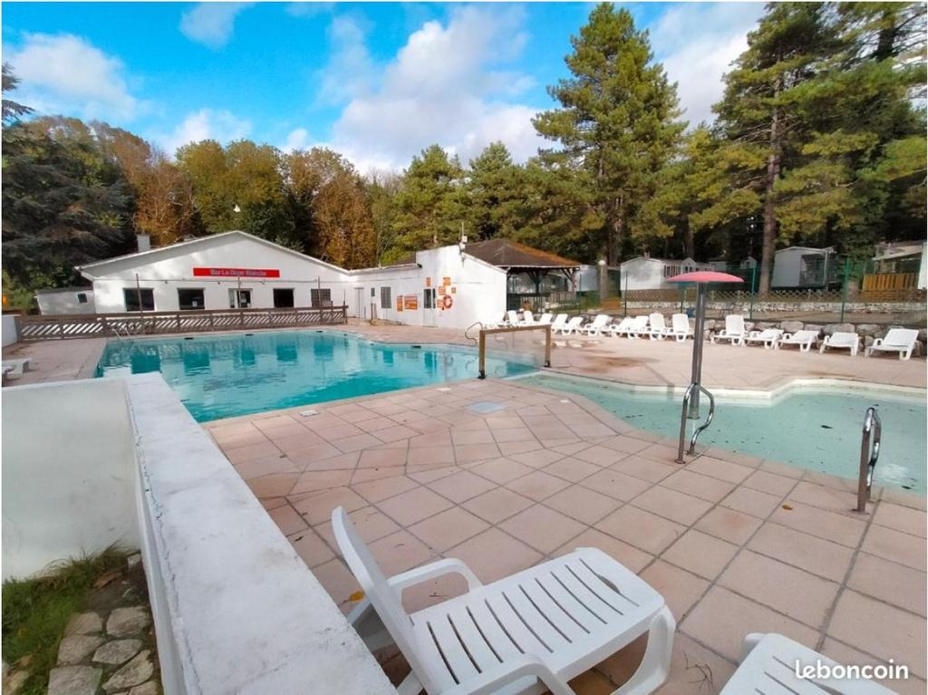 a swimming pool with chairs and an umbrella at Mobil-Home Camping de la dune Blanche in Camiers