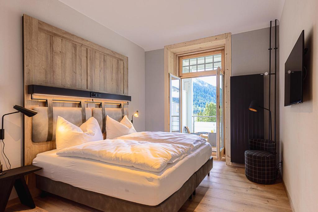 a bedroom with a large bed and a large window at ALPINE INN Davos in Davos