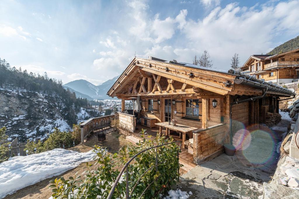 ein Holzhaus in den Bergen mit Schnee in der Unterkunft Alpe Chalets Goldener Hirsch in Scharnitz