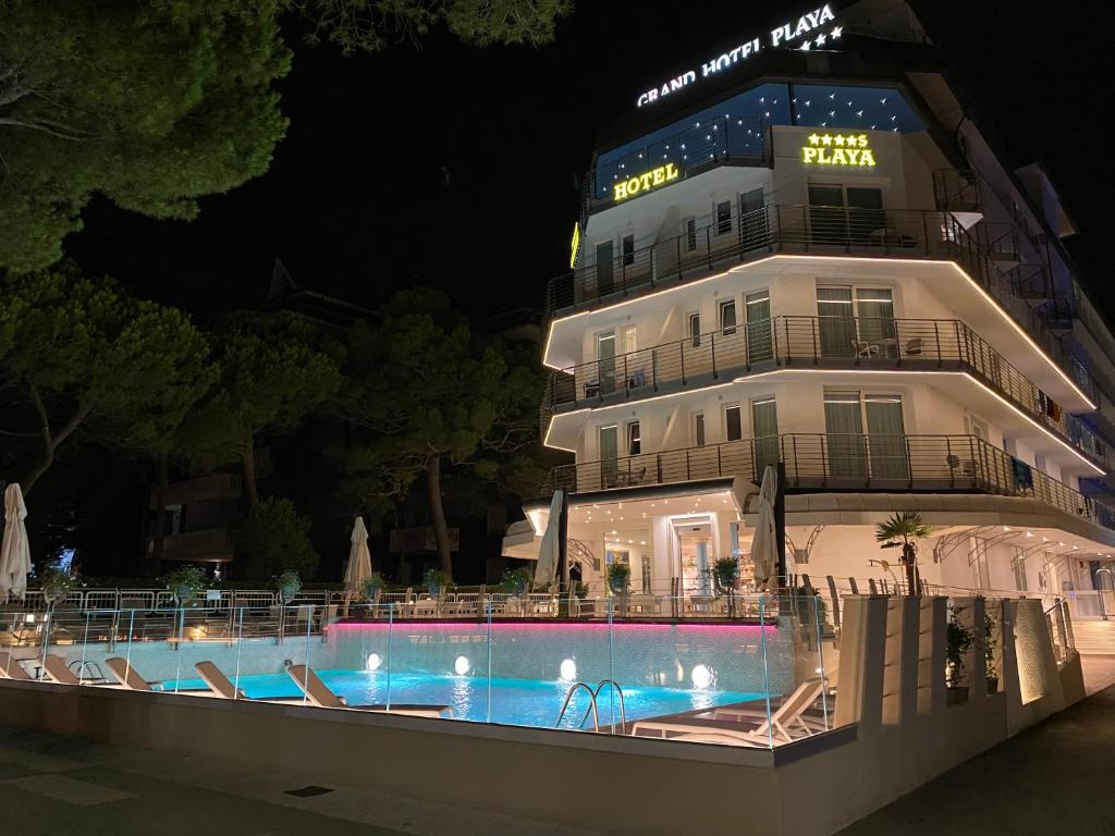 un hotel con piscina di fronte a un edificio di Grand Hotel Playa a Lignano Sabbiadoro