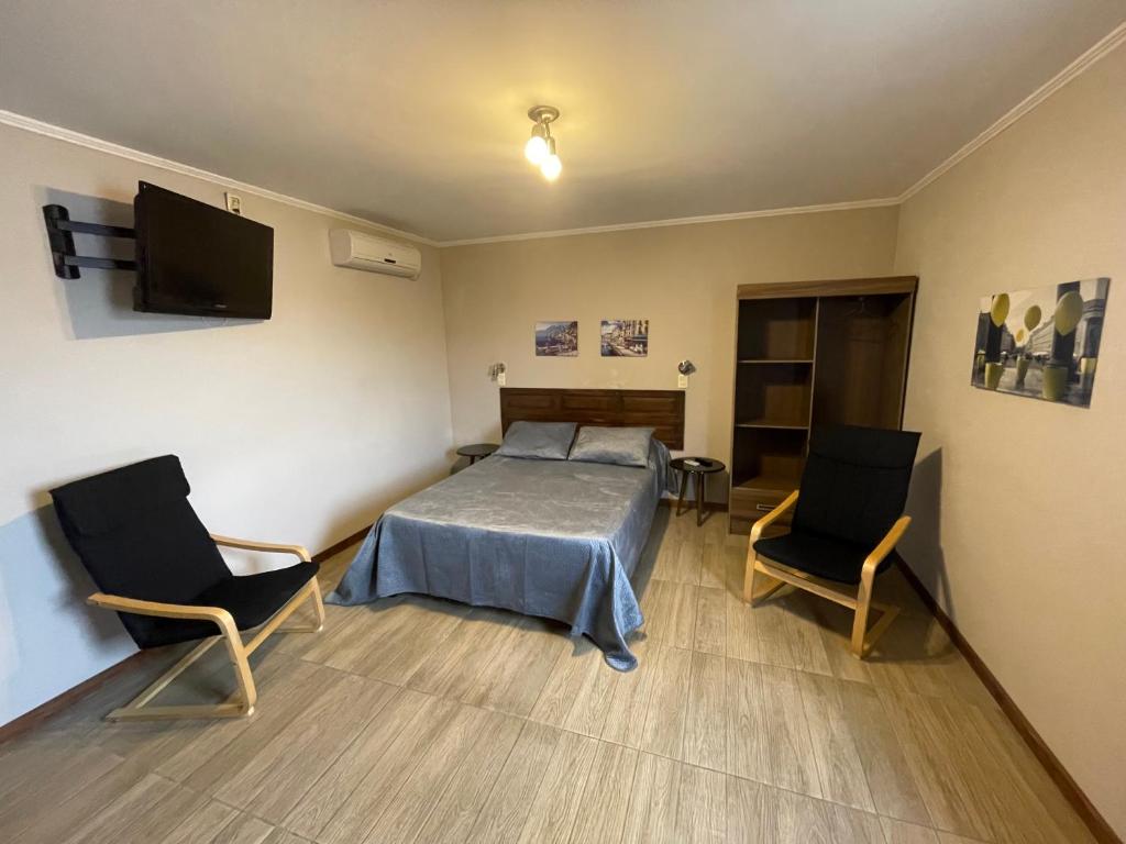 1 dormitorio con 1 cama y 2 sillas en Loft & Suites Centro, en Salto