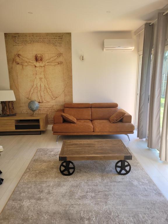 een woonkamer met een bruine bank en een tafel bij La maison des castors -1 flat and 1 studio in Bièvres