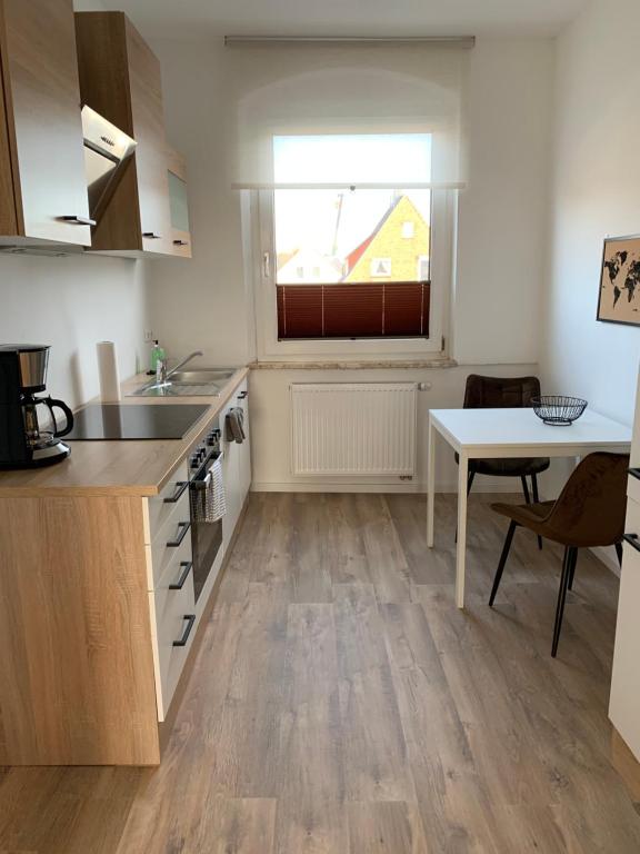 a kitchen with a sink and a table and a window at FEDDERSEN LIVING Moderne Ferienwohnungen - Gemütlich - Netflix - Voll ausgestattet - Waschmaschine - zentral gelegen in Brunsbüttel