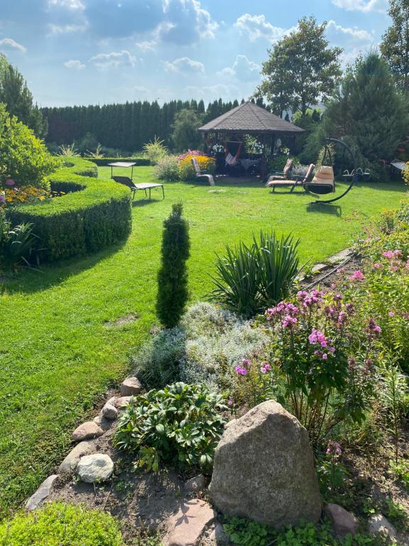 un jardín con bancos y flores y un cenador en Agroturystyka Smulsko en Przykona