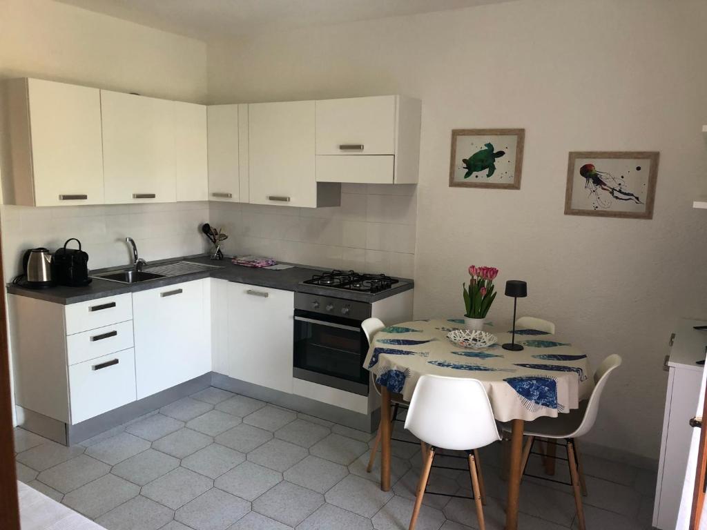 a kitchen with white cabinets and a table with chairs at Centro e Cinta beach free bikes in San Teodoro